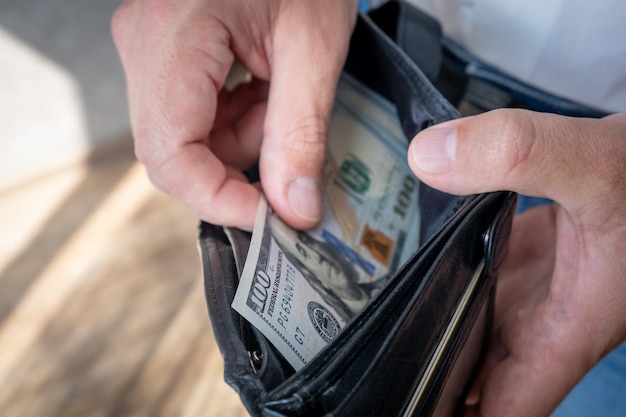 Un uomo in camicia bianca tiene in mano un portafoglio con dei soldi, li conta e li offre a un altro