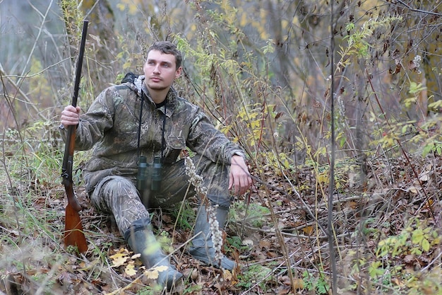 Un uomo in camuffamento e con le armi in una fascia di foresta in una caccia primaverile