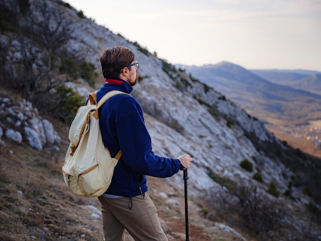 Un uomo in cima a una scogliera nelle montagne primaverili al tramonto e godersi la vista della natura