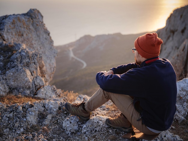 Un uomo in cima a una scogliera nelle montagne primaverili al tramonto e godersi la vista della natura