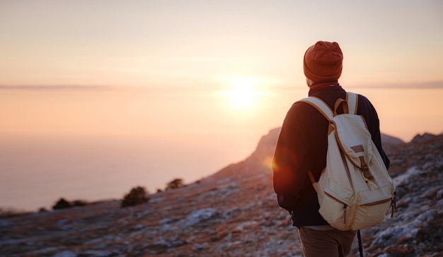 Un uomo in cima a una scogliera nelle montagne primaverili al tramonto e godersi la vista della natura