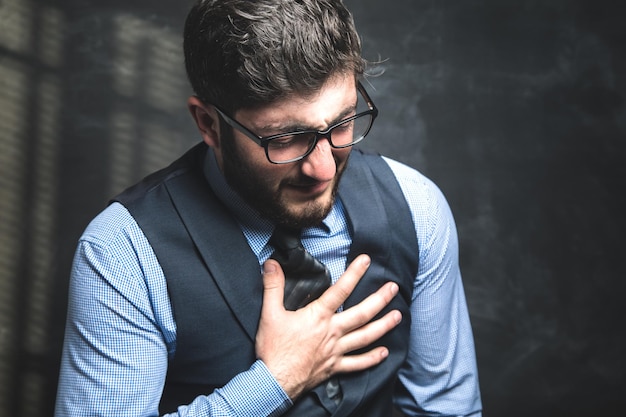 Un uomo in giacca e cravatta ha un attacco di cuore su uno sfondo grigio