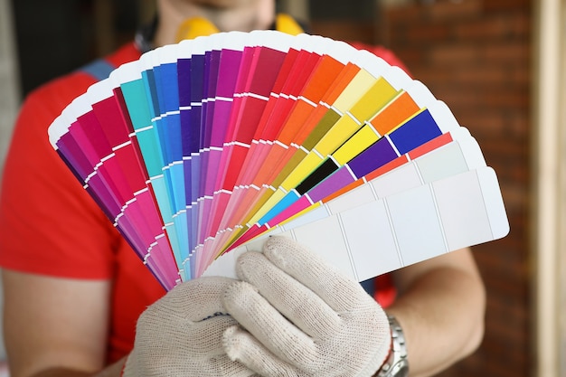 Un uomo in guanti mostra i campioni di colore in un contorno storto una tavolozza di colori per creare