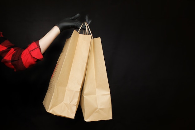 Un uomo in guanti protettivi neri tiene un sacchetto di carta con gli acquisti dal negozio durante le vacanze del venerdì nero.