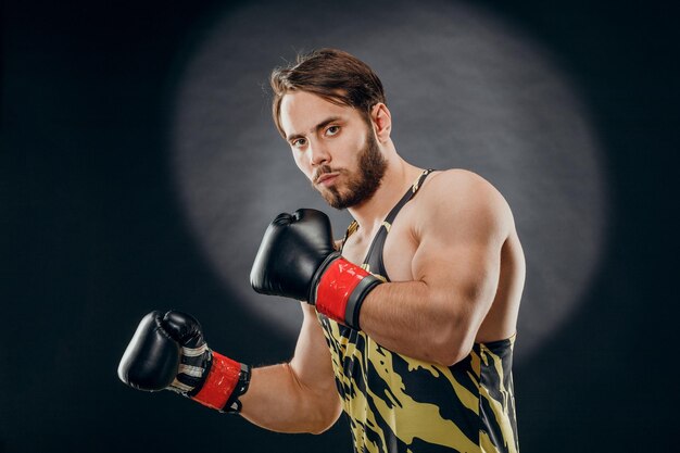 Un uomo in guantoni da boxe. Un uomo di boxe su sfondo nero. Il concetto di uno stile di vita sano.