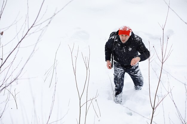Un uomo in inverno nella foresta. Un turista con uno zaino attraversa i boschi in inverno. Ascesa invernale.