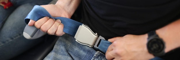 Un uomo in jeans allaccia una cintura di sicurezza in aereo