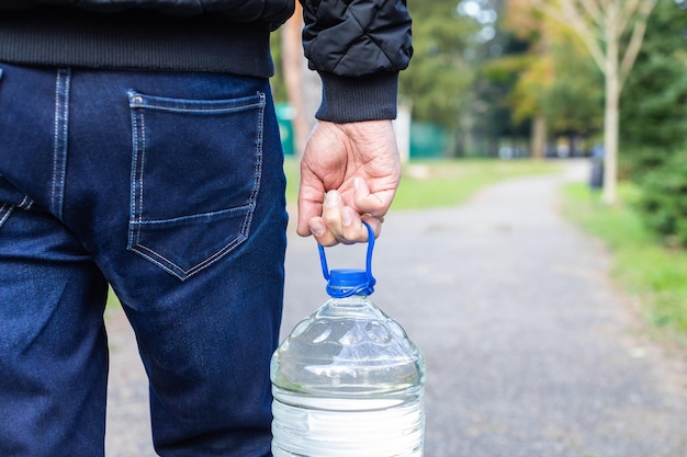 Un uomo in jeans porta una bottiglia d'acqua