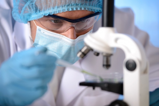 Un uomo in maschera e occhiali sta sperimentando il microscopio.