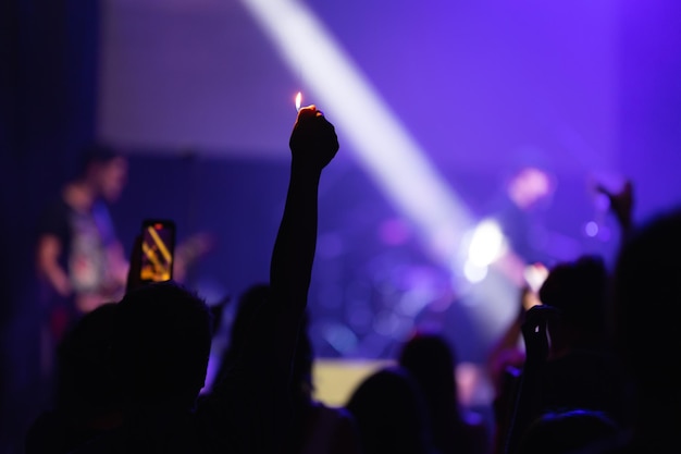 Un uomo in mezzo alla folla alza la mano con un accendino durante un concerto