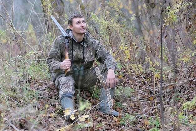 Un uomo in mimetica e con le pistole in una cintura di foresta durante una caccia primaverile