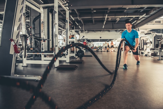 Un uomo in palestra si esercita con una corda.