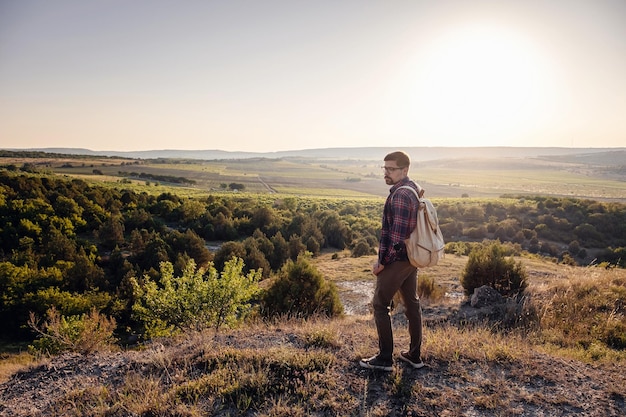 Un uomo in piedi su una montagna mentre il sole tramonta