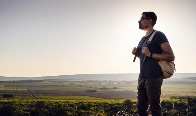 Un uomo in piedi su una montagna mentre il sole tramonta