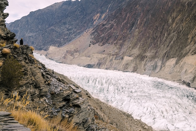 Un uomo in piedi sulla scogliera guardando il ghiacciaio Passu. Pakistan.