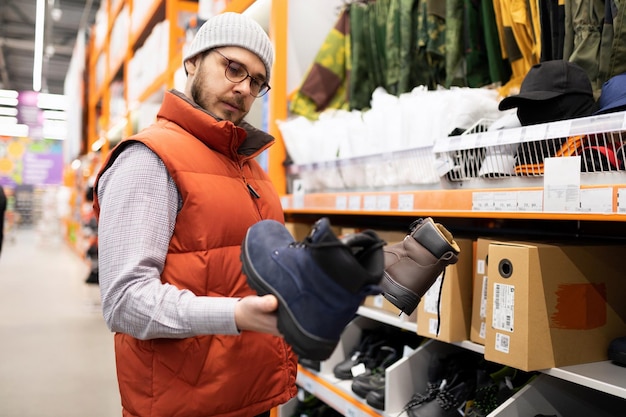 Un uomo in un negozio di ferramenta sceglie scarpe antinfortunistiche per i lavori di costruzione