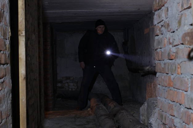 Un uomo in un seminterrato o in una catacomba brilla con una torcia