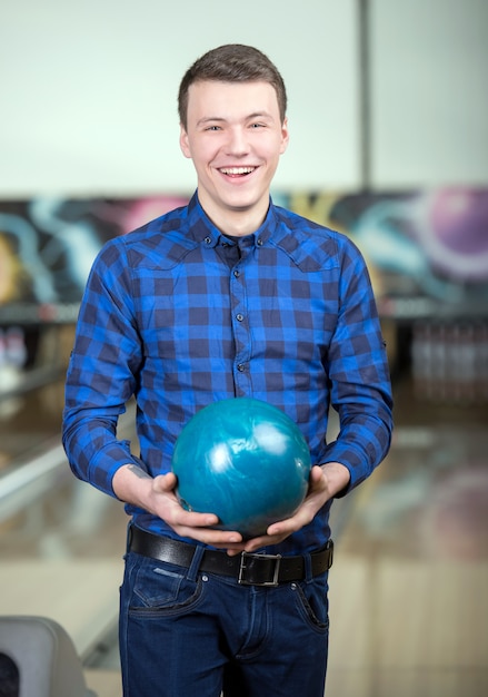 Un uomo in una camicia tiene una palla da bowling.