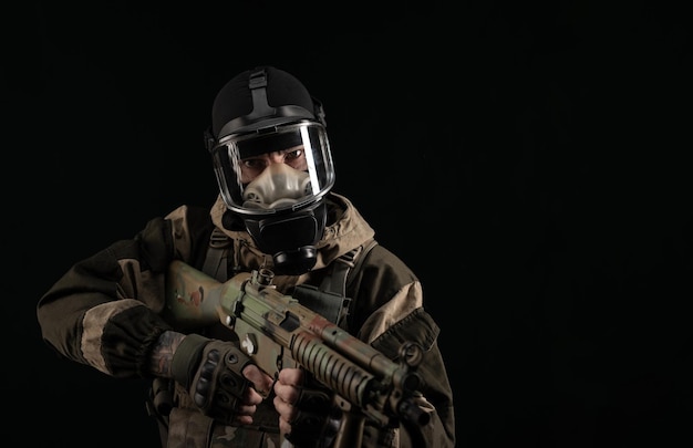 Un uomo in uniforme militare e maschera antigas tiene un'arma con un'espressione arrabbiata di emozione