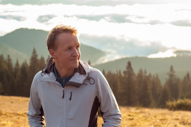 un uomo incontra all'alba il sole sullo sfondo tra montagne e foreste paesaggio turismo trav