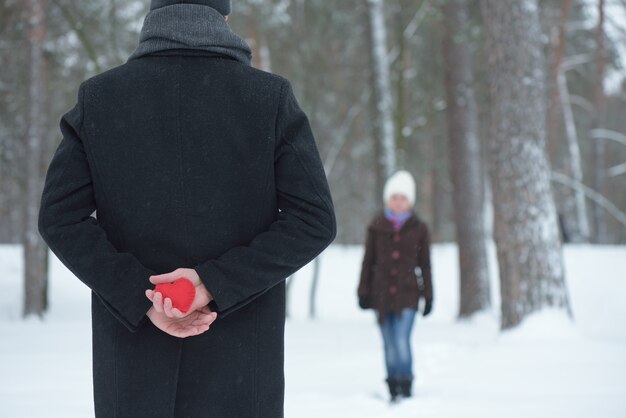 Un uomo incontra la sua donna e nasconde un cuore rosso dietro la schiena