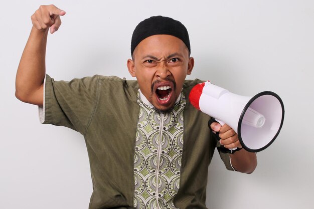 Un uomo indonesiano arrabbiato urla un annuncio tenendo in mano un megafono