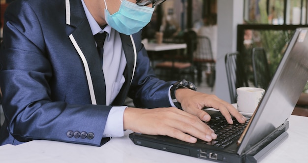 Un uomo indossa una maschera mentre usa un laptop per lavoro