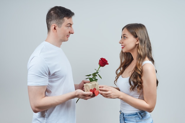 Un uomo innamorato fa un regalo a una bella bionda e una rosa rossa. Buon San Valentino. Proposta di matrimonio.