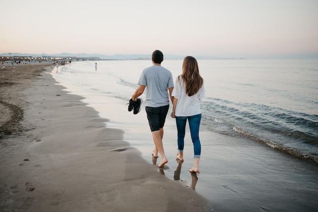 Un uomo ispanico con la sua ragazza sta passeggiando su una spiaggia sabbiosa a Valencia