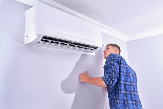 Un uomo ispeziona il condizionatore d'aria a casa, controlla se funziona