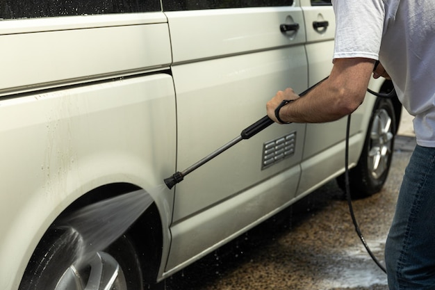 Un uomo lava un'auto in un autolavaggio self-service