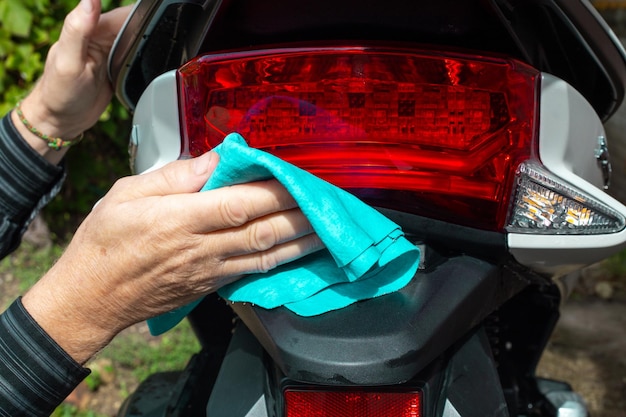 Un uomo lava una moto con uno straccio Manutenzione e cura dei veicoli a motore