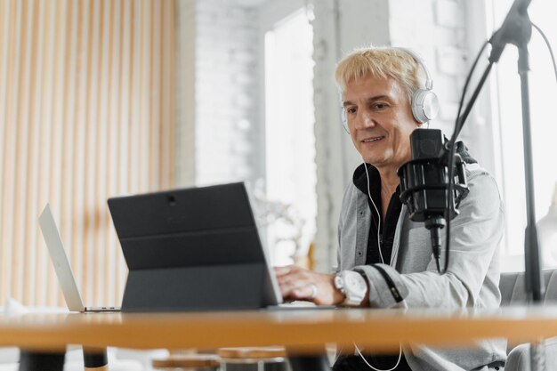 Un uomo lavora come presentatore in una stazione radiofonica che trasmette utilizzando un microfono e un laptop