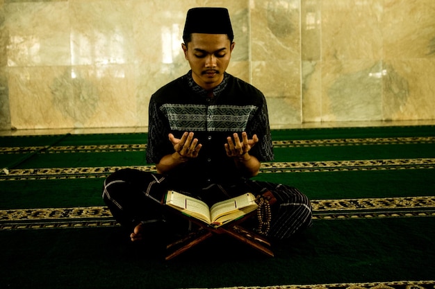 Un uomo legge il Corano in una moschea in Indonesia.