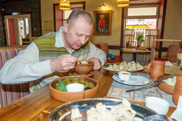 Un uomo mangia cibo in un ristorante con l'immagine di una donna sul muro dietro di lui.