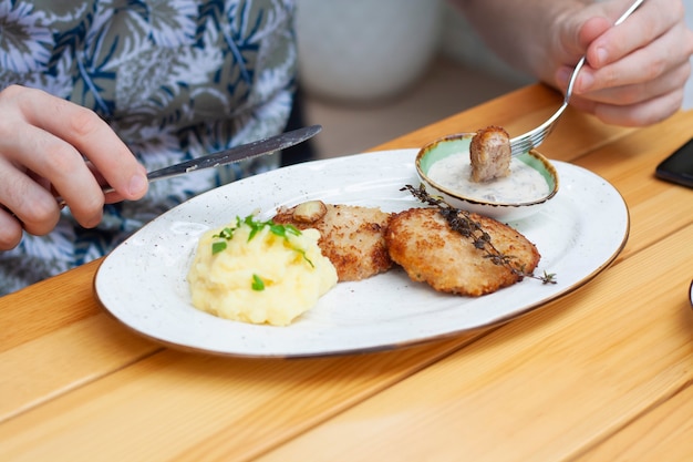 Un uomo mangia cotolette di carne con purè di patate in un ristorante