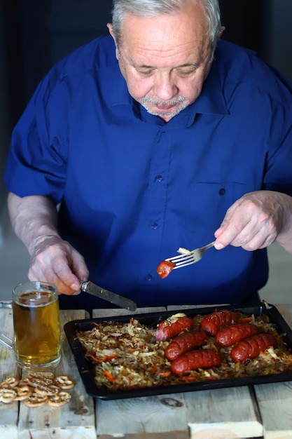 Un uomo mangia salsicce con cavolo