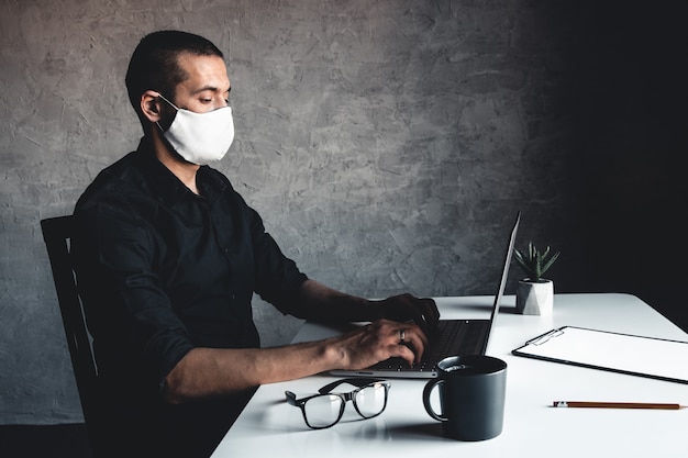 Un uomo mascherato lavora al computer