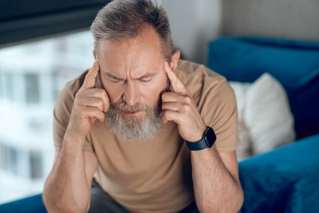 Un uomo maturo con la barba che soffre di mal di testa