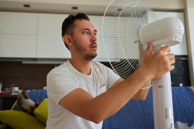 Un uomo maturo lavora per installare un ventilatore a pale sul soffitto di casa