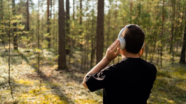 Un uomo medita ascoltando musica calma con le cuffie in armonia con la natura