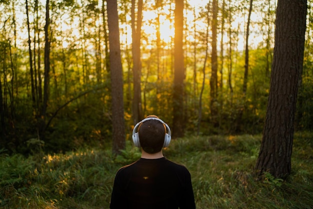 Un uomo medita ascoltando musica calma con le cuffie in armonia con la natura