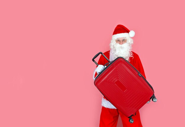 Un uomo moderno in costume da Babbo Natale con una valigia in mano pronto per un nuovo viaggio