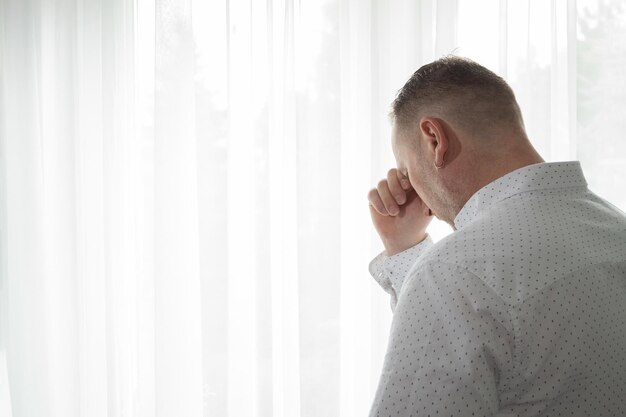 Un uomo moderno piange stando alla finestra