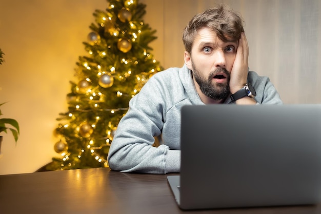 Un uomo molto stanco siede in ufficio di notte la notte di Natale tiene la testa pensierosa con la mano