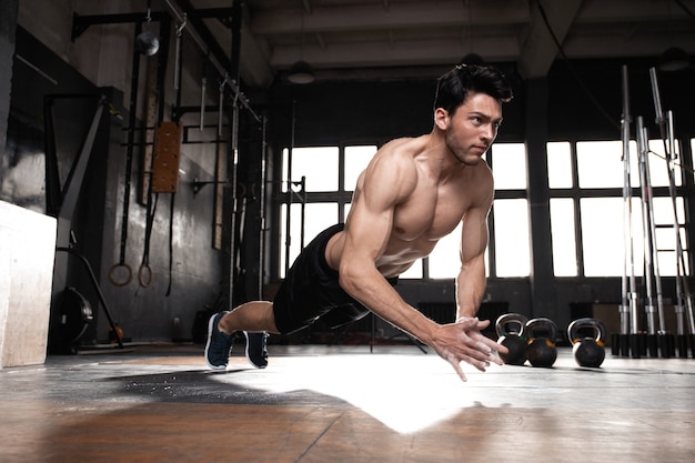 Un uomo muscoloso che fa flessioni in palestra.