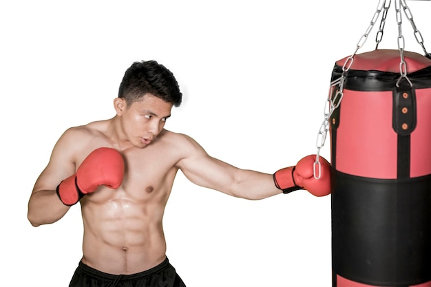 Un uomo muscoloso colpisce una borsa da boxe nello studio.