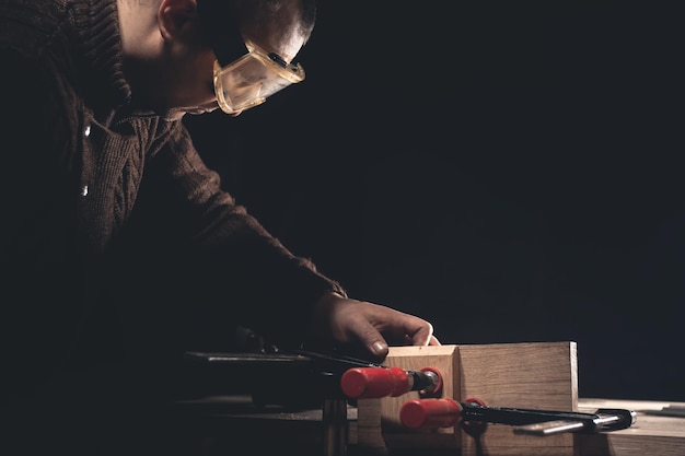 Un uomo realizza prodotti in legno con l'aiuto di strumenti speciali. Ritratto di giovane falegname al lavoro. Occupazione nel settore della lavorazione del legno