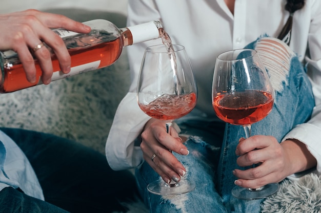 Un uomo riempie i bicchieri di vino rosato