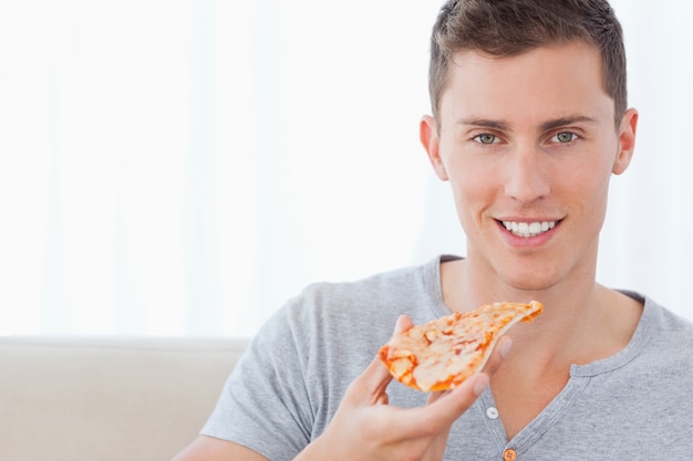 Un uomo seduto mentre tiene in mano una fetta di pizza